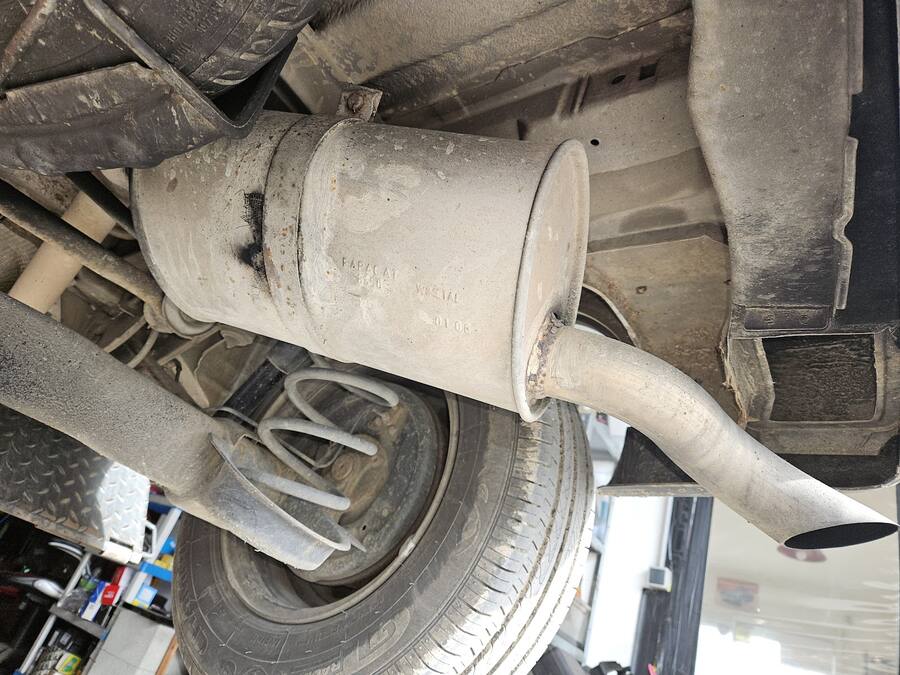 Silencieux d'échappement vu sous une voiture levée sur le pont