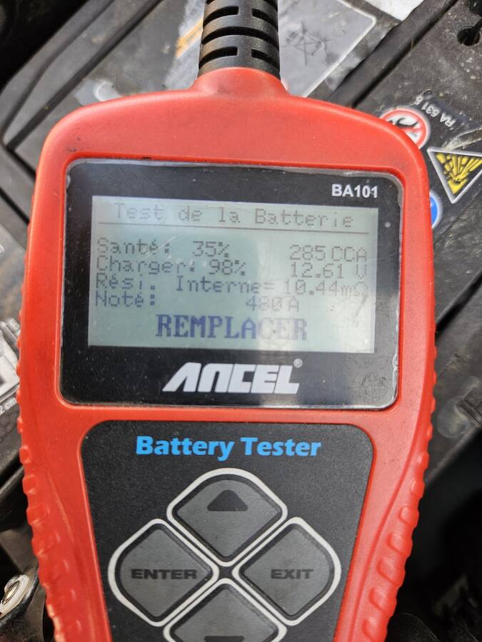 Testeur de batterie branché à l'atelier, l'écran indique de remplacer la batterie